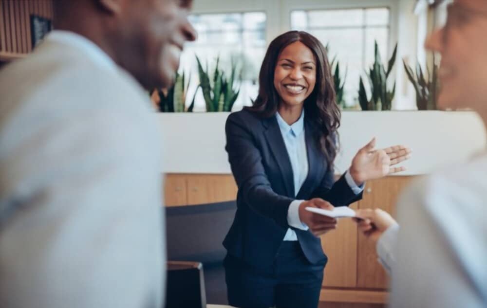 Femme souriante accueillant des clients dans le cadre d’un service de conciergerie premium, offrant assistance et conseils personnalisés
